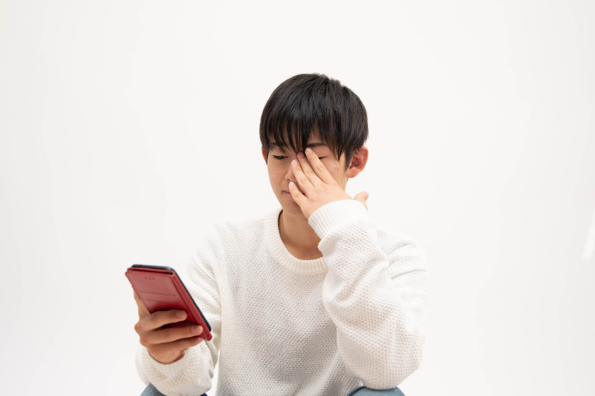 目を疲れた様子のスマホを持つ男性