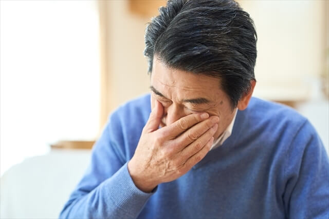 頭痛に悩む中年男性の表情