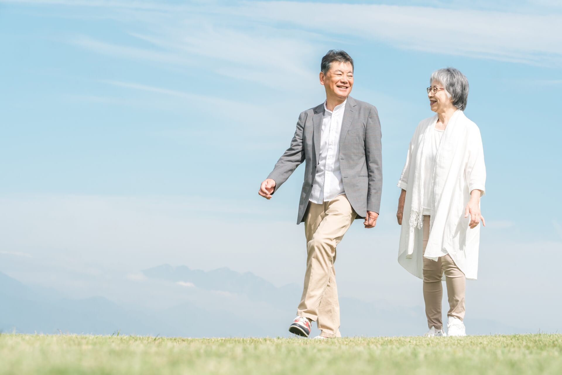 青空の下で散歩するシニア夫婦