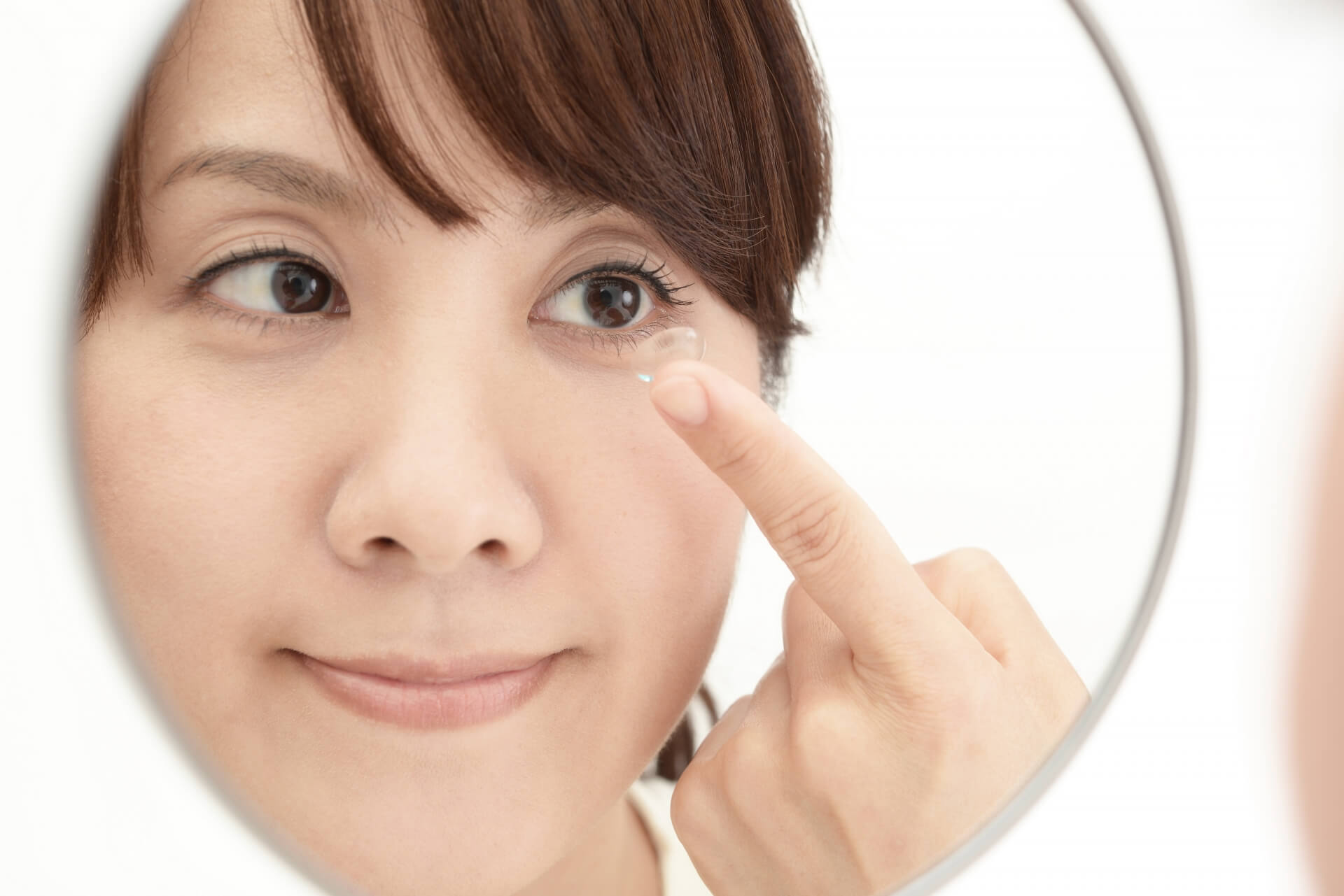 鏡で肌をチェックする女性